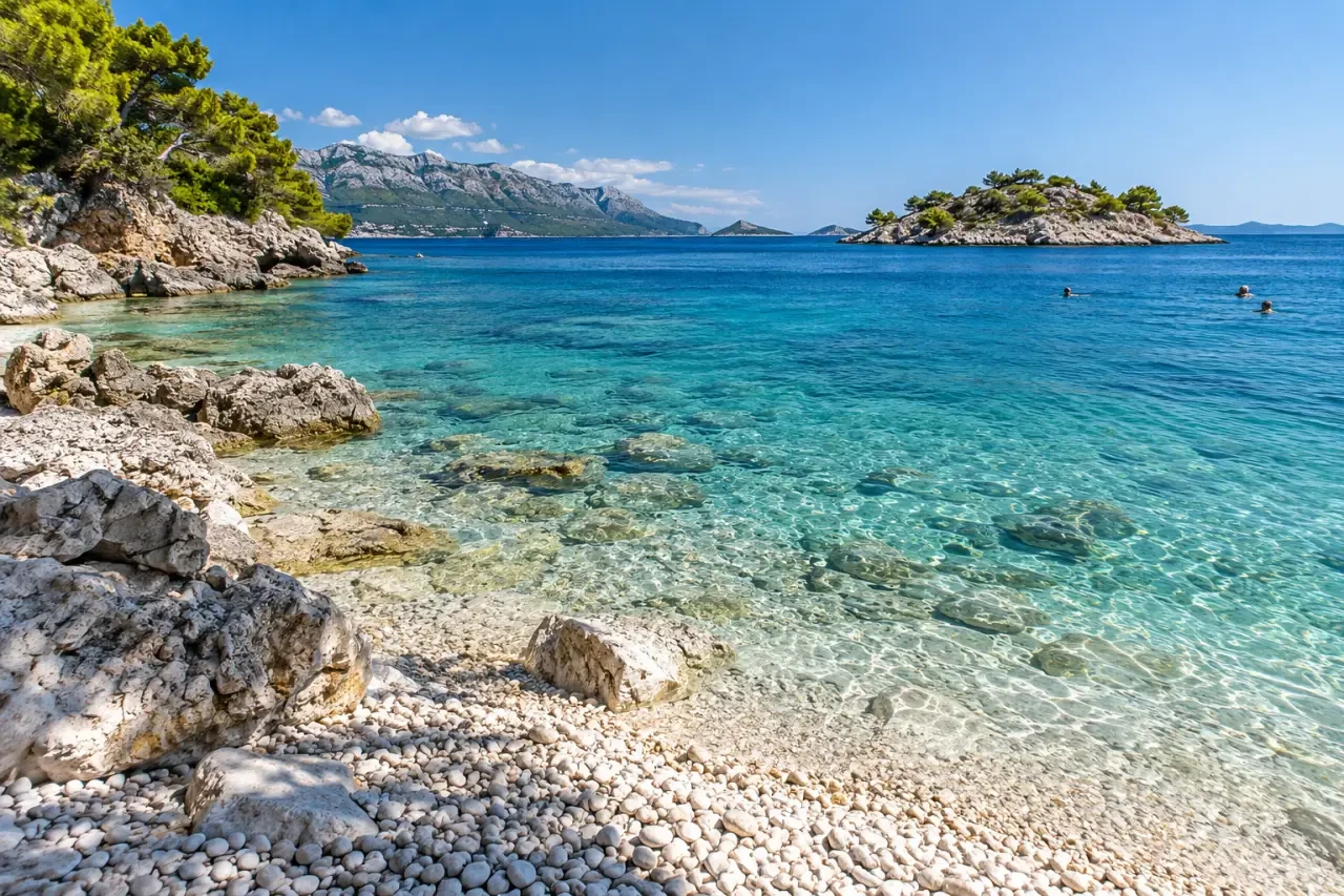 Vacances en Croatie bord de mer avec plage de galets, eau turquoise et îles croates